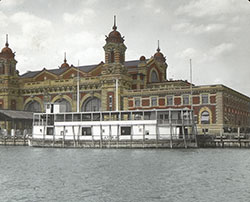 United States Immigration Station building on Ellis Island. A ferry named "Laura" is docked in front of the building. c. 1900